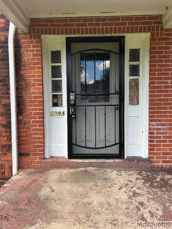 doorway to property featuring brick siding