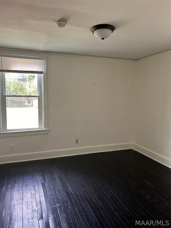 unfurnished room with dark wood finished floors and baseboards