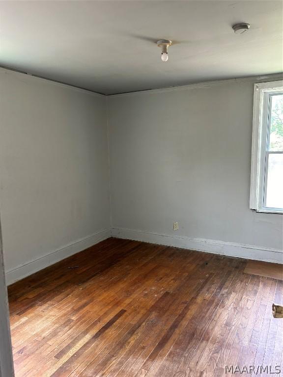 unfurnished room featuring dark wood-type flooring and baseboards