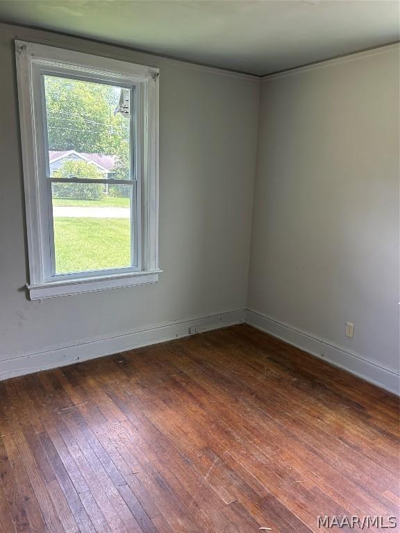 spare room featuring dark wood-style flooring and baseboards