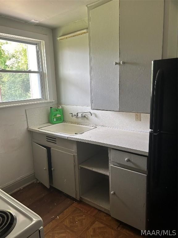 kitchen with light countertops, a sink, freestanding refrigerator, and electric stove