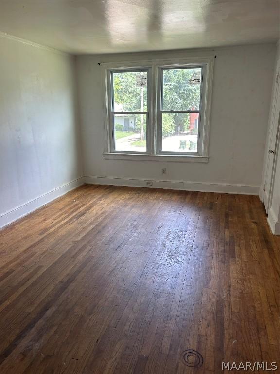 unfurnished room with baseboards and dark wood finished floors