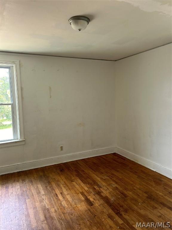 empty room with dark wood-type flooring and baseboards