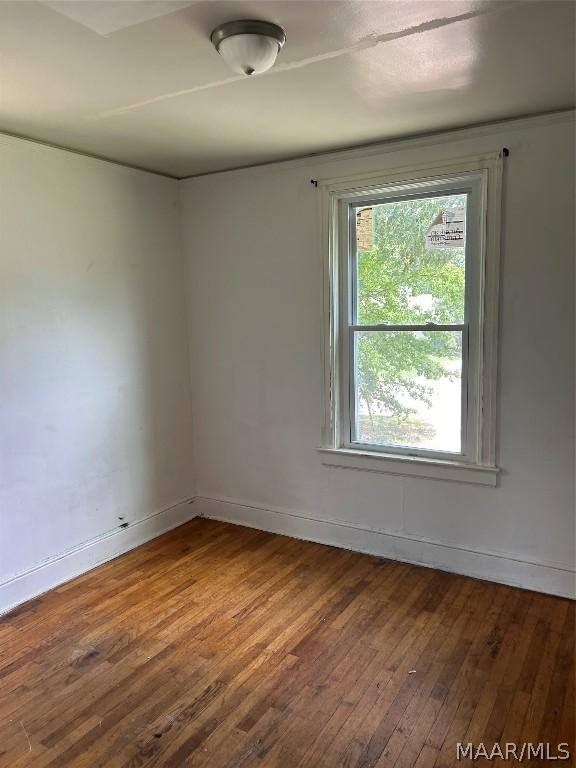 spare room featuring dark wood-style flooring and baseboards