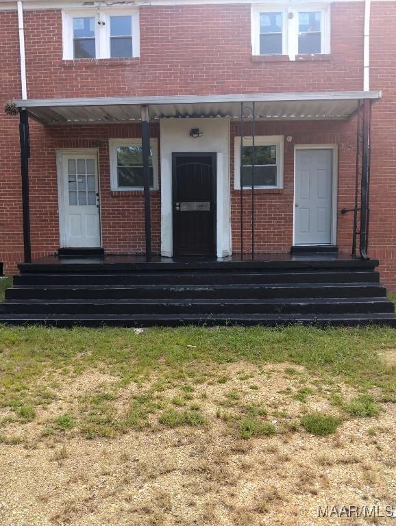 view of exterior entry featuring a yard and brick siding