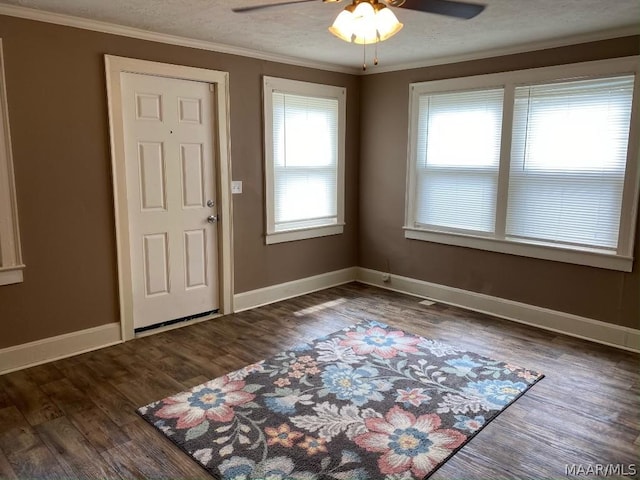 foyer with ceiling fan, dark wood-type flooring, a wealth of natural light, and ornamental molding