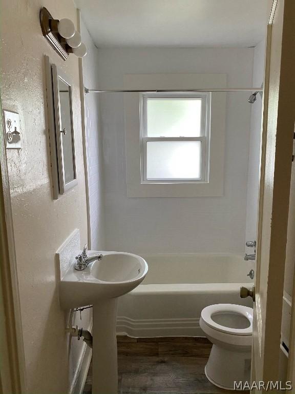 bathroom featuring toilet, hardwood / wood-style floors, and shower / bathing tub combination