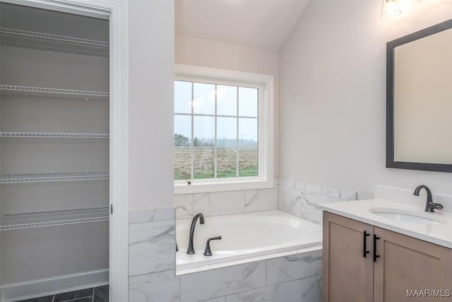 full bath featuring a garden tub, vaulted ceiling, and vanity