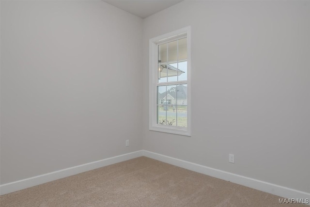 empty room featuring light carpet and baseboards