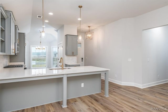 kitchen with light wood-style flooring, a chandelier, gray cabinets, and a sink