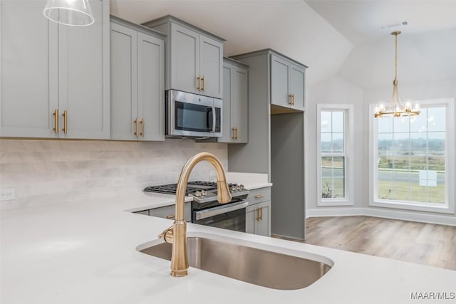 kitchen featuring stainless steel appliances, light countertops, a wealth of natural light, and gray cabinetry