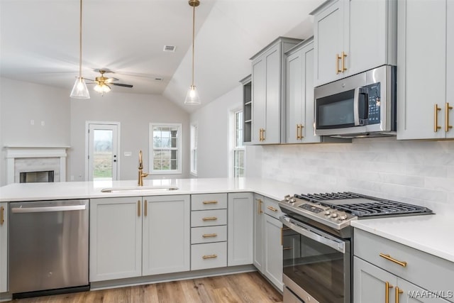 kitchen featuring stainless steel appliances, a peninsula, a sink, and gray cabinetry