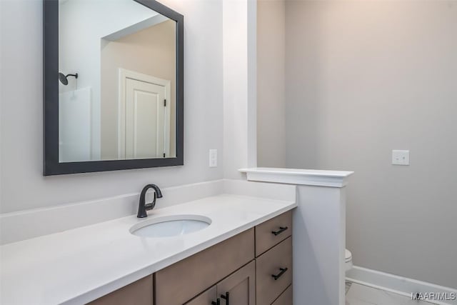 bathroom featuring baseboards, vanity, and toilet