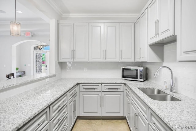 1426 Barret Park Way, Montgomery, AL 36117 - kitchen featuring stainless steel microwave, tasteful backsplash, ornamental molding, light stone countertops, and arched walkways