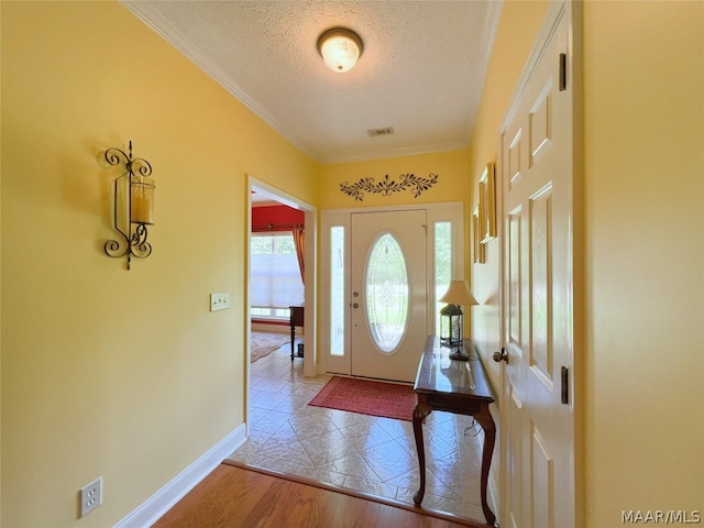 entryway featuring crown molding, a textured ceiling, and light hardwood / wood-style floors