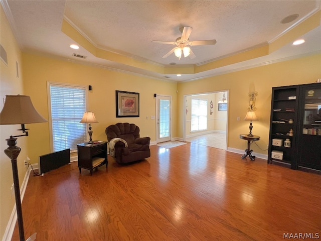 sitting room featuring ornamental molding, a raised ceiling, hardwood / wood-style floors, and a wealth of natural light