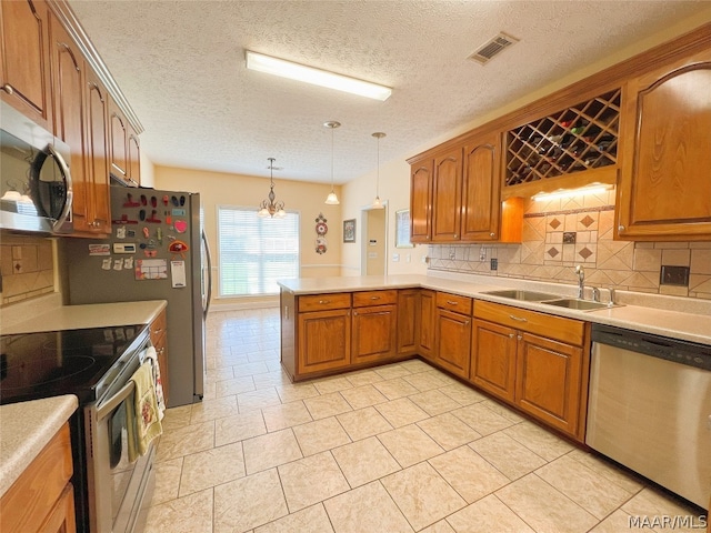 kitchen with pendant lighting, sink, kitchen peninsula, stainless steel appliances, and a textured ceiling