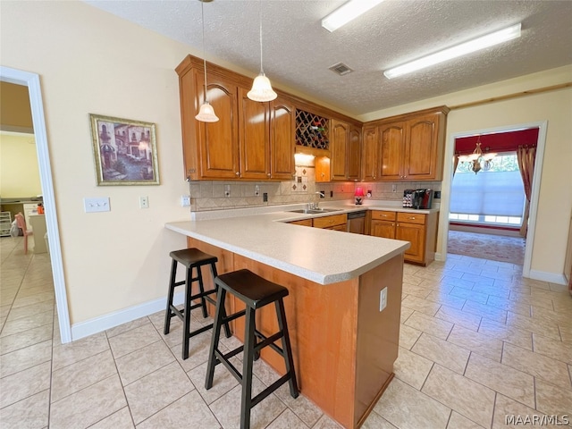 kitchen with tasteful backsplash, hanging light fixtures, kitchen peninsula, and a textured ceiling