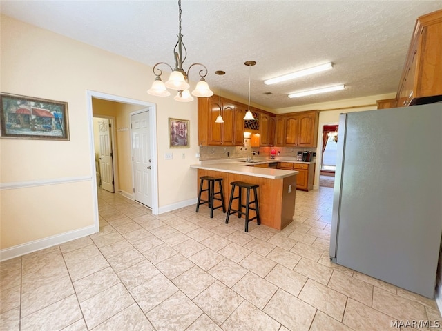 kitchen with pendant lighting, stainless steel fridge, a breakfast bar, a textured ceiling, and kitchen peninsula