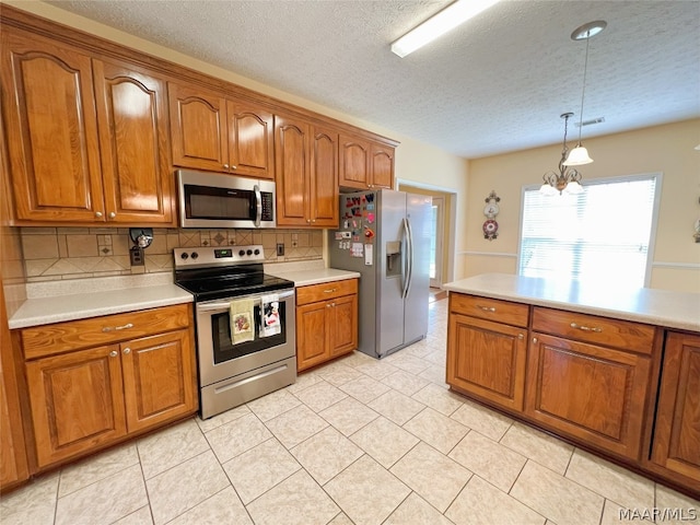 kitchen with pendant lighting, an inviting chandelier, stainless steel appliances, tasteful backsplash, and a textured ceiling