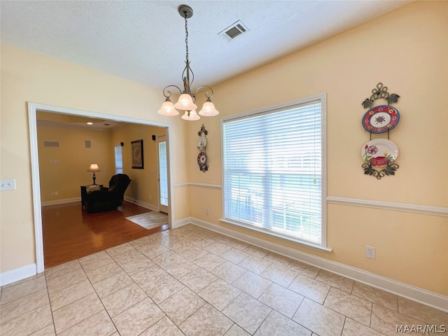 empty room with an inviting chandelier and light tile patterned floors