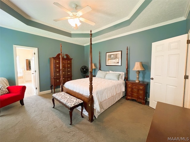 carpeted bedroom featuring ornamental molding, a tray ceiling, ceiling fan, and ensuite bath