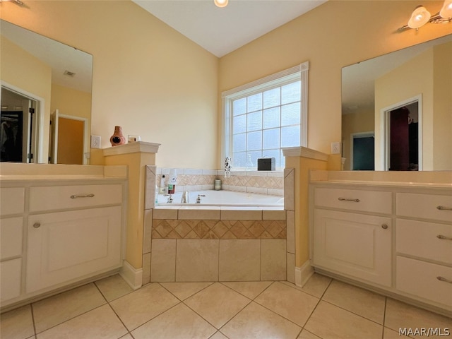 bathroom featuring tiled tub, vanity, and tile patterned floors