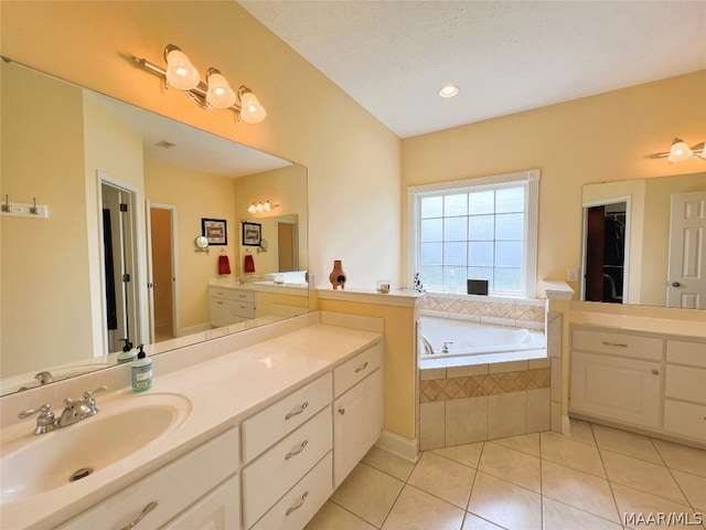 bathroom featuring vanity, tiled bath, tile patterned flooring, and a textured ceiling