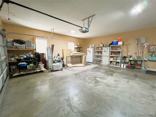 garage with a garage door opener and white fridge