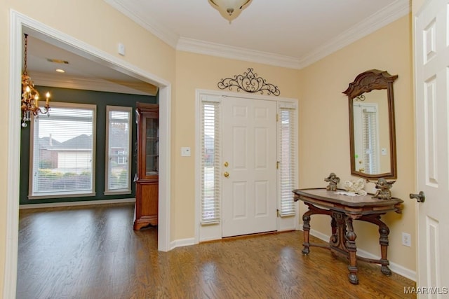 entrance foyer featuring a notable chandelier, dark wood-type flooring, and ornamental molding