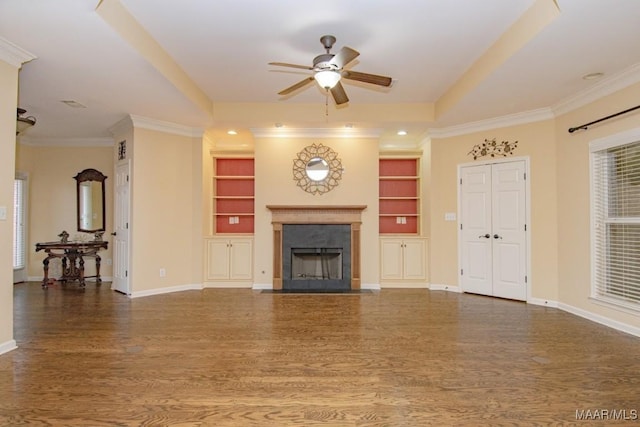 unfurnished living room with crown molding, dark wood-type flooring, built in features, and ceiling fan