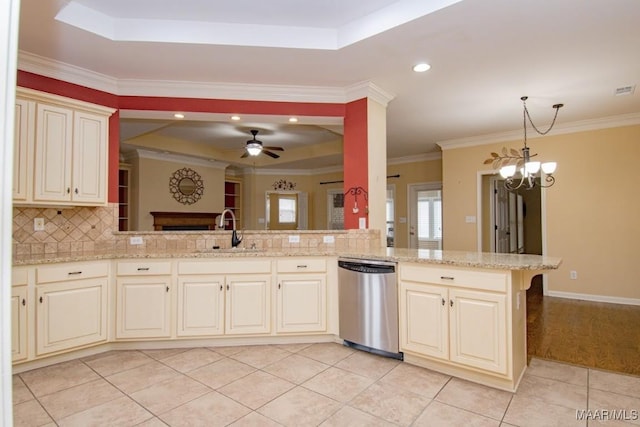 kitchen featuring kitchen peninsula, sink, stainless steel dishwasher, a tray ceiling, and light stone countertops