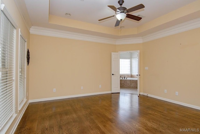 empty room with ceiling fan, ornamental molding, dark hardwood / wood-style floors, and a raised ceiling