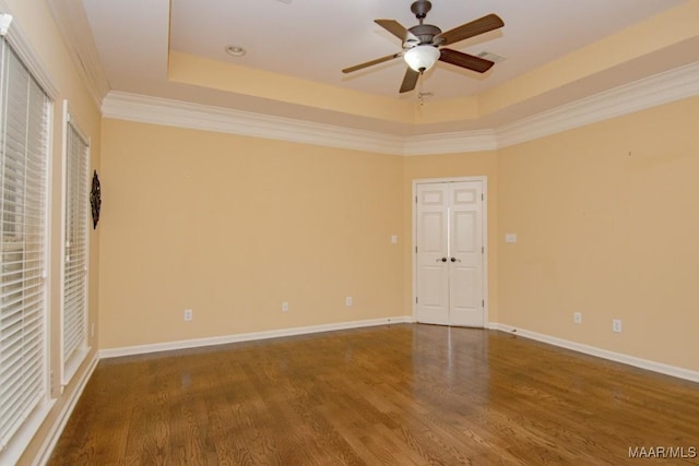 unfurnished bedroom featuring hardwood / wood-style flooring, ornamental molding, ceiling fan, and a tray ceiling