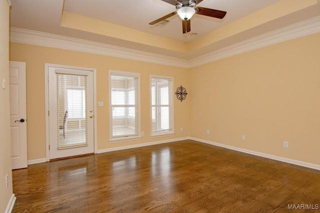 unfurnished room featuring a raised ceiling, ceiling fan, ornamental molding, and dark hardwood / wood-style flooring