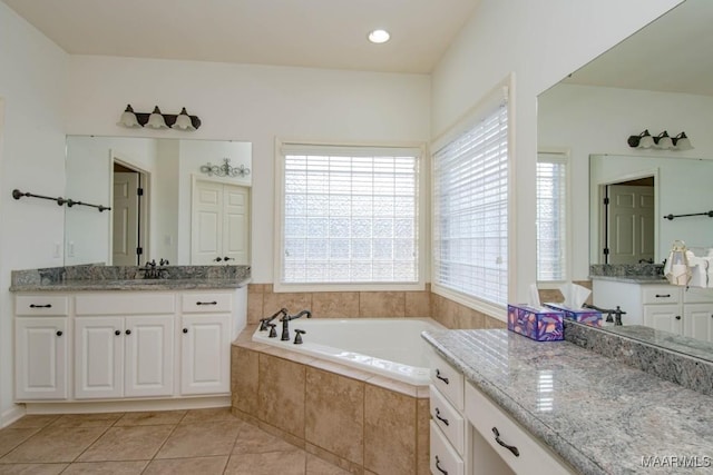 bathroom featuring tile patterned floors, vanity, and tiled bath