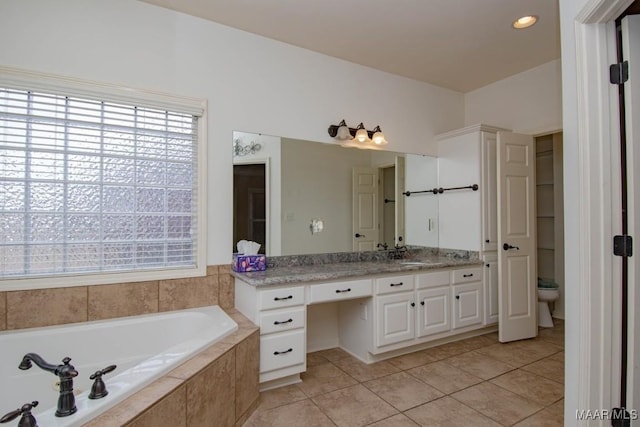 bathroom with vanity, tiled tub, tile patterned flooring, and toilet