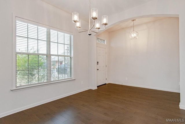 empty room featuring dark hardwood / wood-style flooring and an inviting chandelier