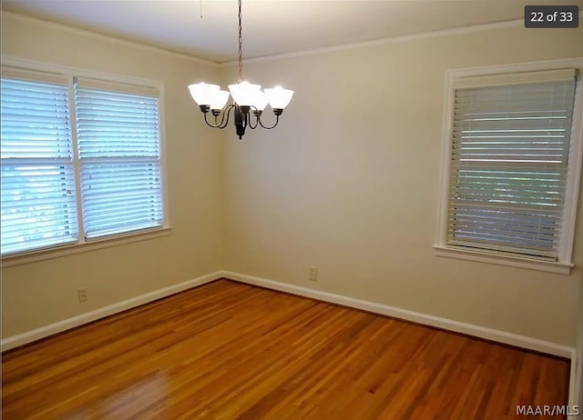 unfurnished room with a notable chandelier, crown molding, and hardwood / wood-style floors