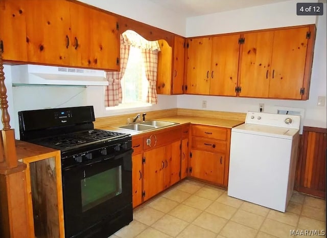 kitchen featuring black gas stove, ventilation hood, sink, washer / dryer, and light tile patterned floors