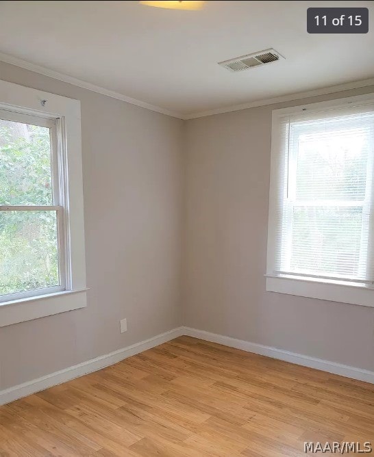 spare room featuring crown molding, plenty of natural light, and light hardwood / wood-style floors