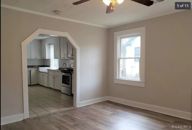 kitchen featuring sink, tasteful backsplash, stainless steel range with electric stovetop, light wood-type flooring, and ornamental molding