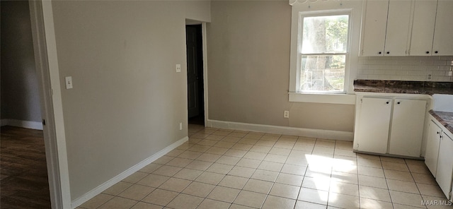 kitchen featuring white cabinetry, decorative backsplash, and light tile patterned flooring