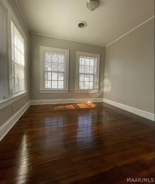empty room featuring ornamental molding, dark wood-style floors, and baseboards