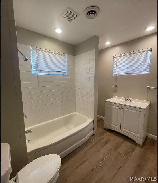 full bath with wood finished floors, tub / shower combination, toilet, recessed lighting, and baseboards