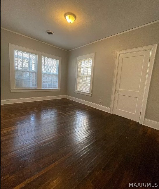 unfurnished room with crown molding, baseboards, and dark wood-type flooring