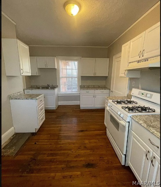 kitchen featuring white gas range oven, under cabinet range hood, a textured ceiling, dark wood-style floors, and white cabinetry