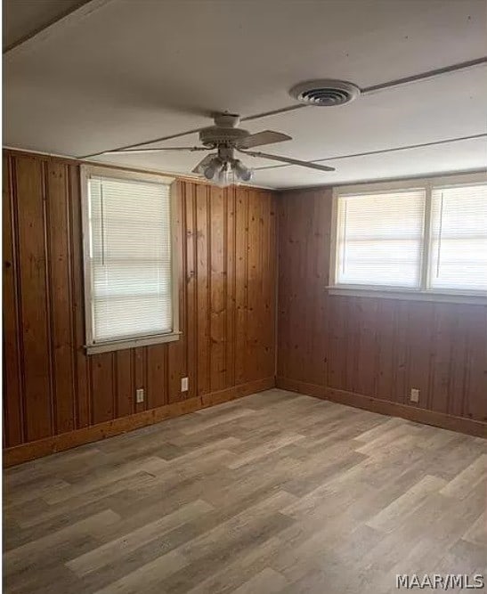 empty room with wooden walls, hardwood / wood-style floors, and ceiling fan