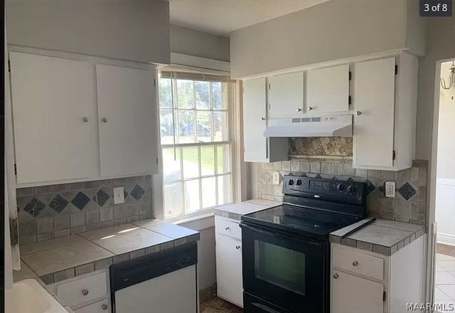 kitchen with black electric range oven, dishwasher, exhaust hood, and tile countertops