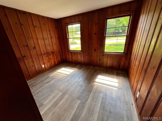 spare room featuring light hardwood / wood-style floors and wooden walls